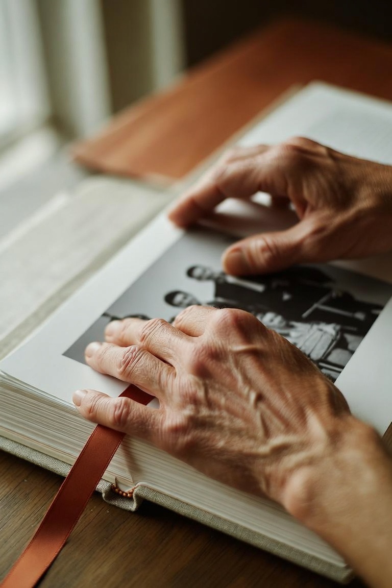 Hands resting on an open hardcover memory book showing a black-and-white photograph
